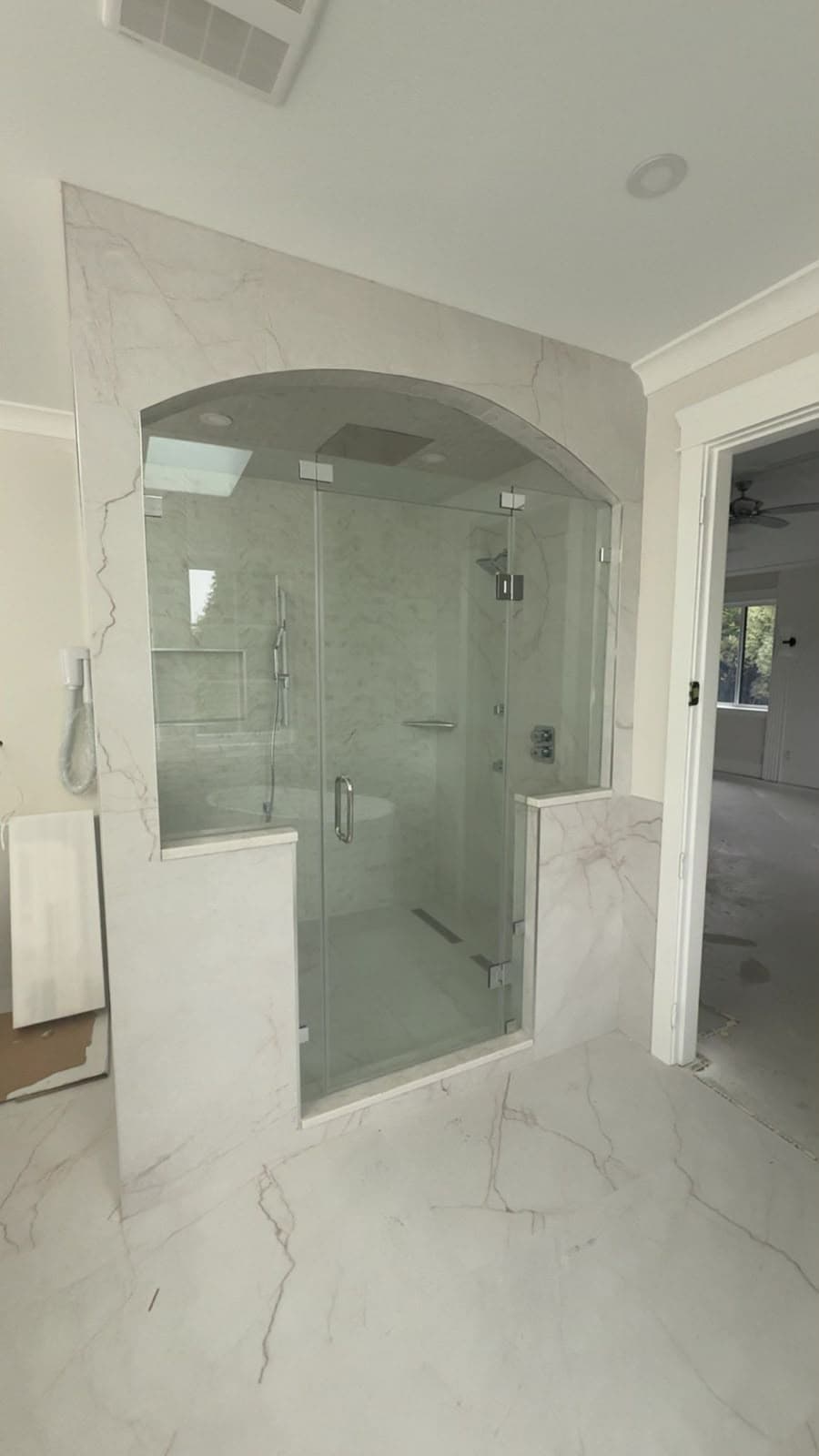 Walk-in glass shower in an arched stone surround